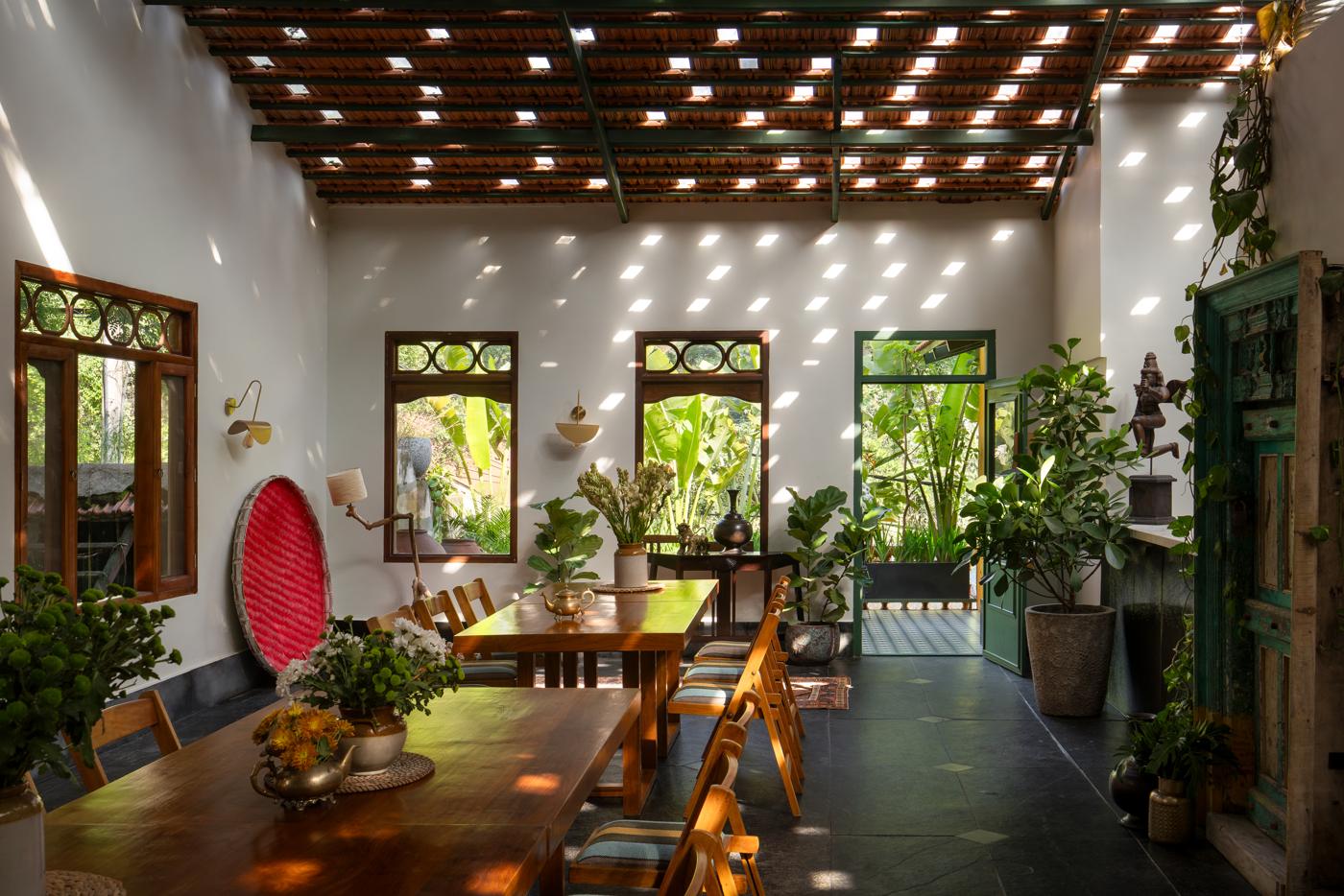 Main dining room with a clay-tile ceiling, long timber tables, folding chairs and large windows onto greenery