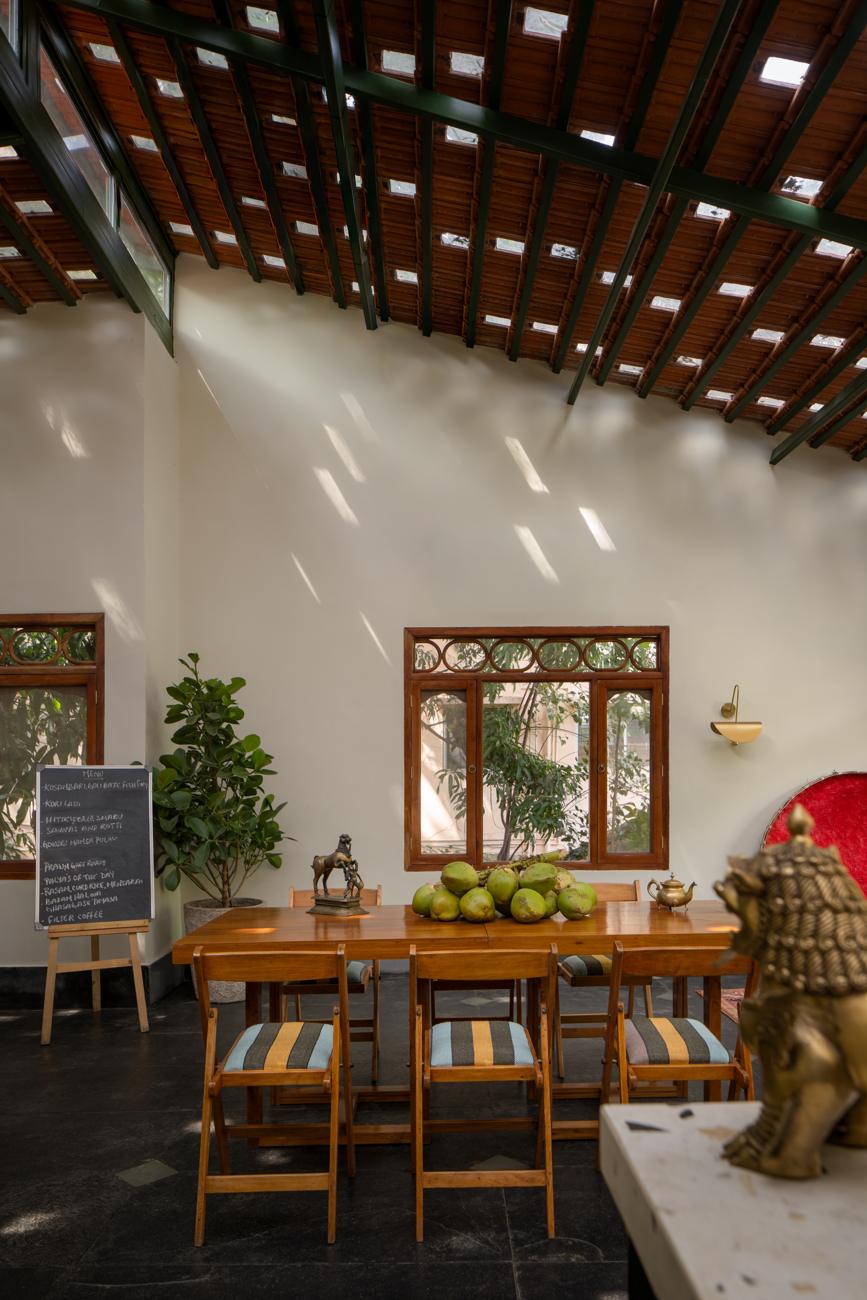 Dining room with a long table set with coconuts and a brass lion, a chalkboard sign and carved windows