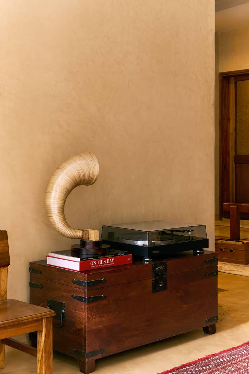 Timber trunk with iron fittings holding a turntable, a gramophone horn and books, in front of a warm plastered wall