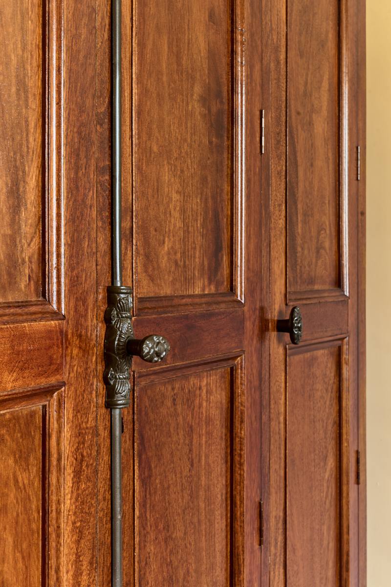 Close view of panelled timber wardrobe doors with a cast iron latch and knobs