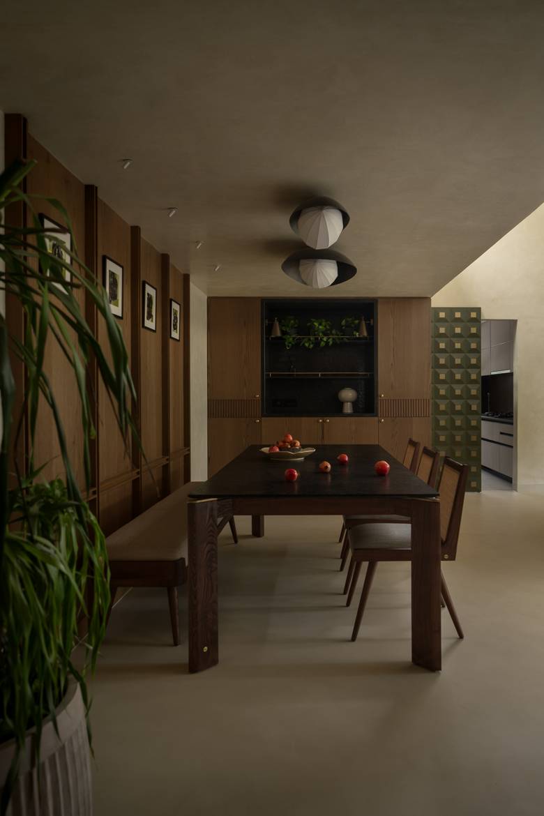 Dining table with a bench and cane-backed chairs under two ceiling lights, with a green geometric tiled doorway to the kitchen