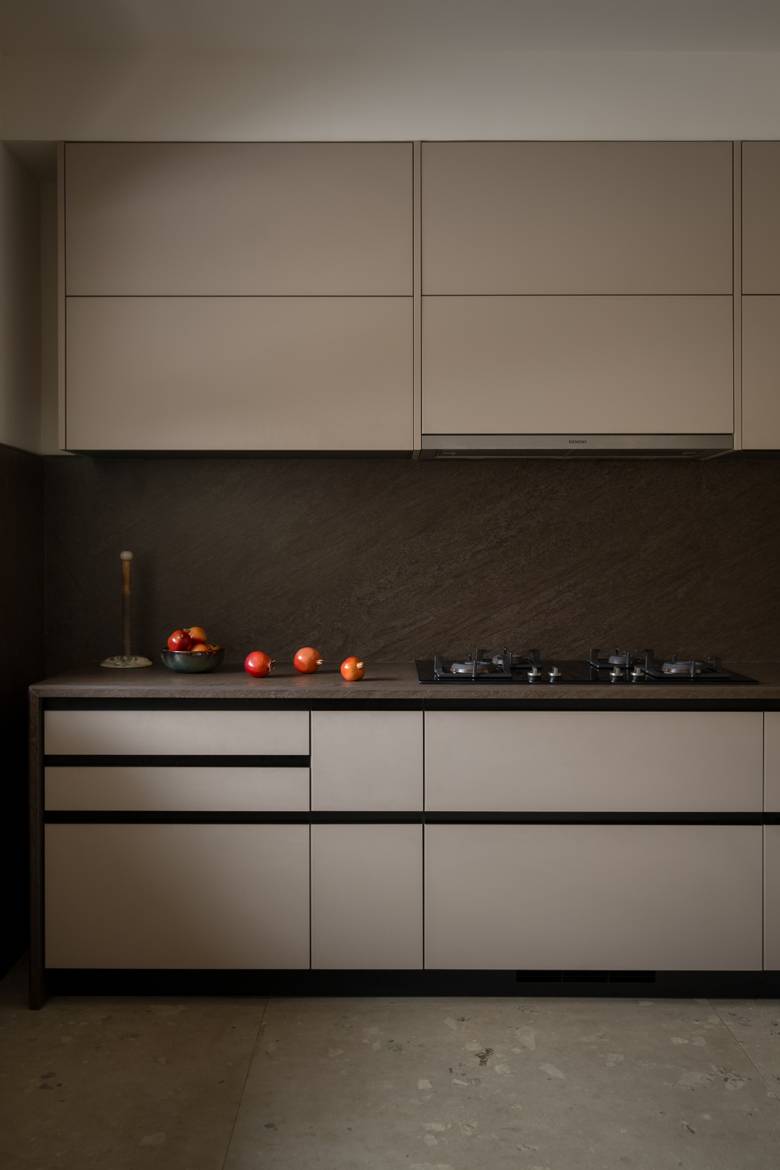 Kitchen with greige flat-panel cabinets, a dark stone backsplash and counter, a gas hob and pomegranates in a bowl
